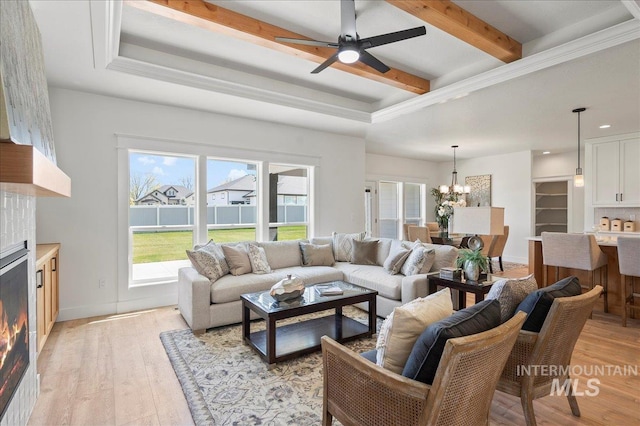 living room featuring ceiling fan with notable chandelier, ornamental molding, and light hardwood / wood-style flooring