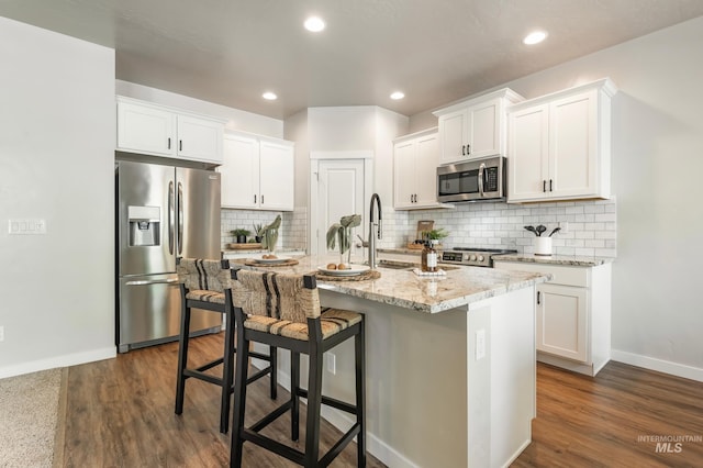 6135 N Morpheus Ave, Meridian, ID 83642 - kitchen with appliances with stainless steel finishes, an island with sink, a kitchen breakfast bar, white cabinets, and recessed lighting