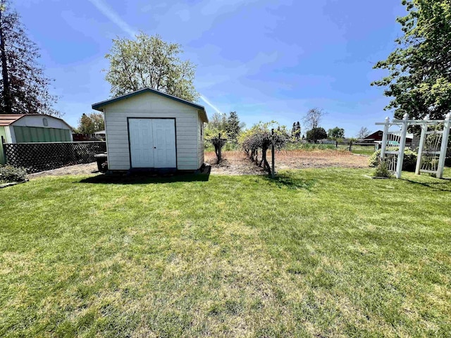 view of yard with an outdoor structure, fence, and a shed