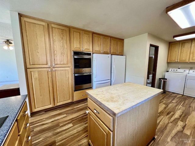 kitchen with washer and clothes dryer, wood finished floors, freestanding refrigerator, double oven, and a center island