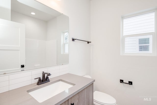 bathroom featuring vanity, decorative backsplash, and toilet