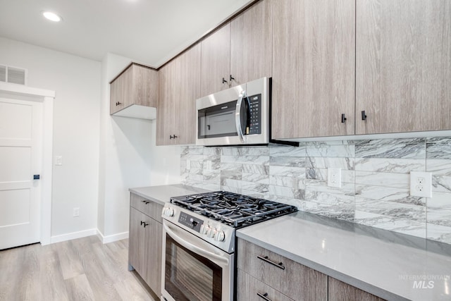 kitchen with tasteful backsplash, appliances with stainless steel finishes, light brown cabinetry, and light hardwood / wood-style flooring