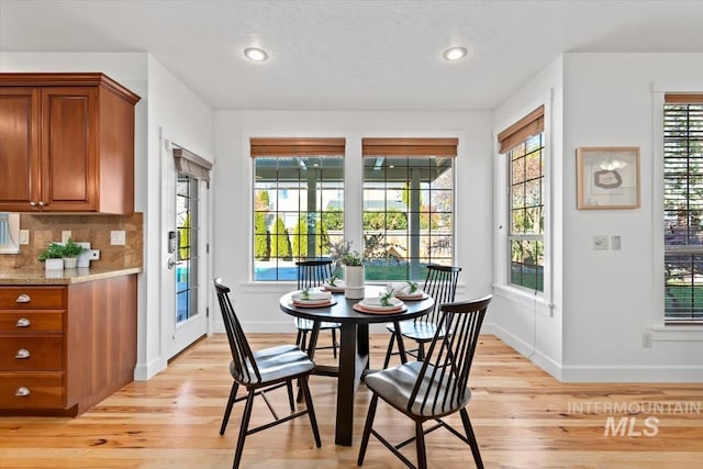 dining area featuring light wood-type flooring, plenty of natural light, and a textured ceiling