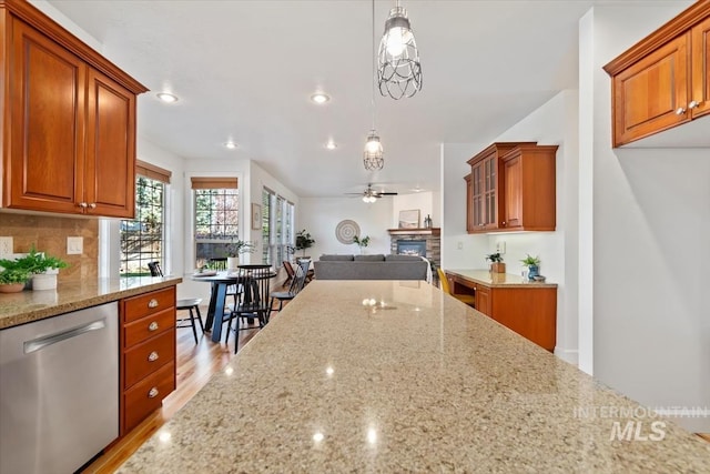 kitchen featuring dishwasher, light wood-type flooring, light stone counters, and pendant lighting