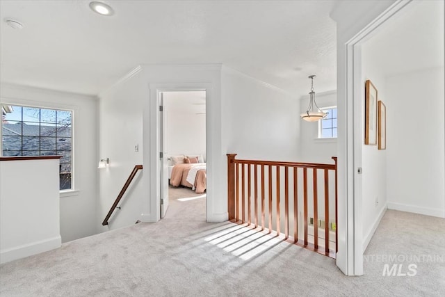 hallway with light colored carpet and crown molding