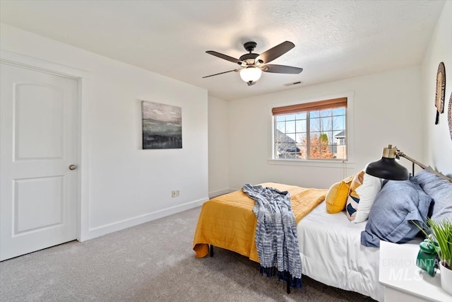 bedroom with a textured ceiling, carpet floors, and ceiling fan