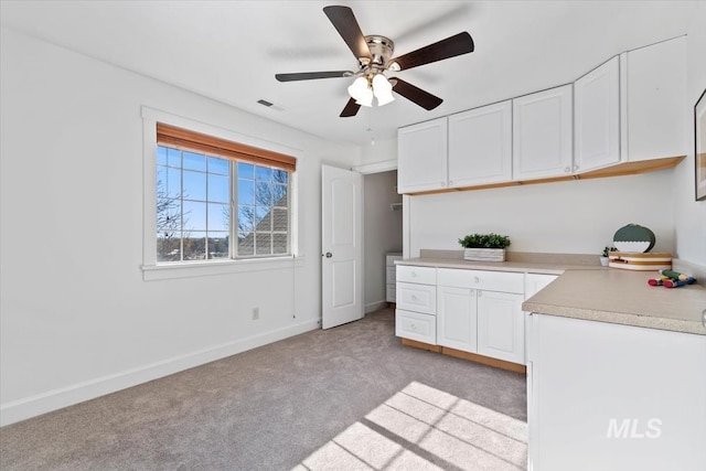 kitchen with white cabinets, light colored carpet, and ceiling fan