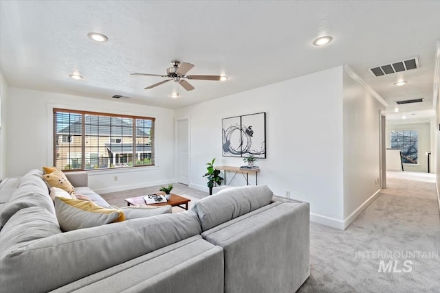 living room with ceiling fan, light colored carpet, and ornamental molding