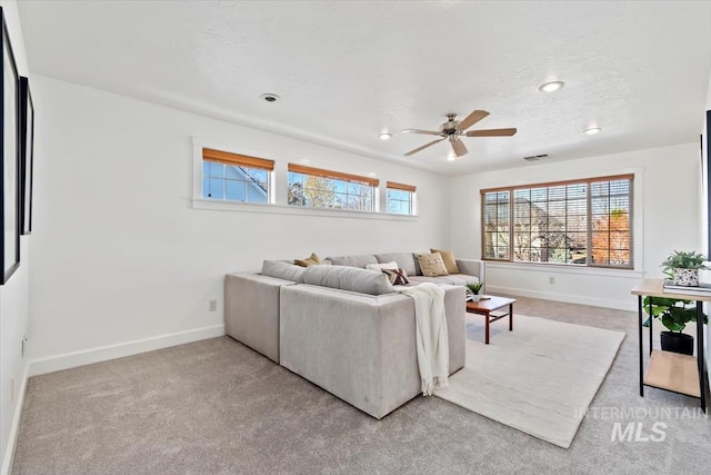 carpeted living room with a textured ceiling and ceiling fan