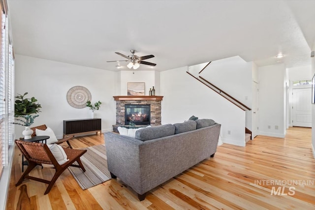 living room featuring a stone fireplace, hardwood / wood-style flooring, and ceiling fan