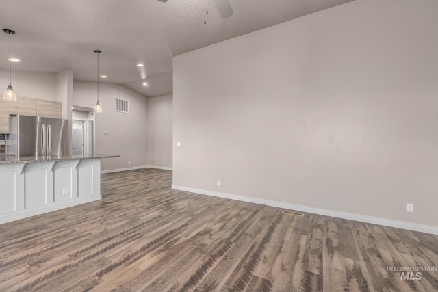 unfurnished living room with dark hardwood / wood-style flooring, lofted ceiling, a textured ceiling, and ceiling fan