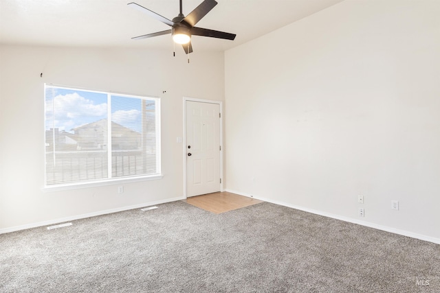 spare room featuring vaulted ceiling, baseboards, a ceiling fan, and light colored carpet