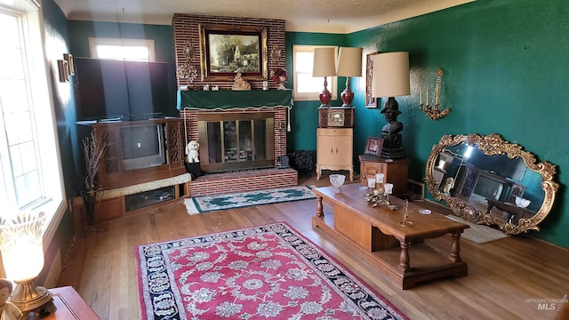 sitting room with wood-type flooring and a brick fireplace