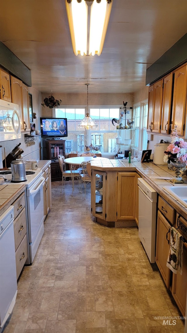 kitchen with white appliances, tile countertops, and decorative light fixtures