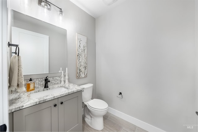 bathroom with toilet, baseboards, and vanity