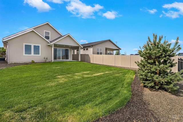 back of house featuring stucco siding, fence, cooling unit, and a yard