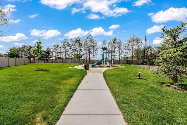 surrounding community featuring a playground, fence, and a lawn