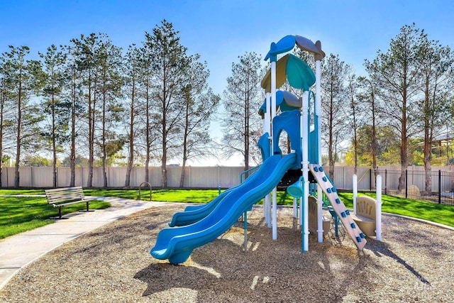 communal playground featuring a lawn and fence