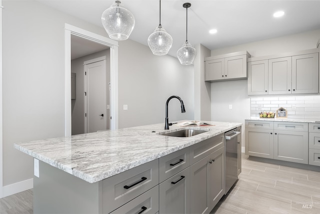 kitchen featuring dishwasher, tasteful backsplash, gray cabinets, and a sink