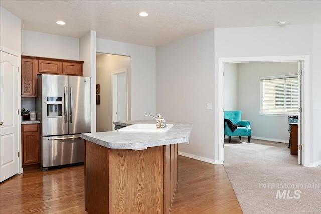 182 New Hampshire Way, Twin Falls, ID 83301 - kitchen featuring stainless steel fridge, light countertops, an island with sink, brown cabinets, and dark wood-style floors