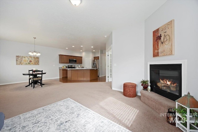 182 New Hampshire Way, Twin Falls, ID 83301 - living area with light colored carpet, baseboards, a chandelier, a glass covered fireplace, and recessed lighting