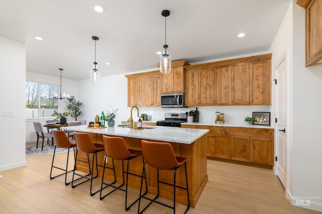 2041 W Gelding St, Middleton, ID 83644 - kitchen with appliances with stainless steel finishes, a sink, light wood finished floors, a center island with sink, and backsplash