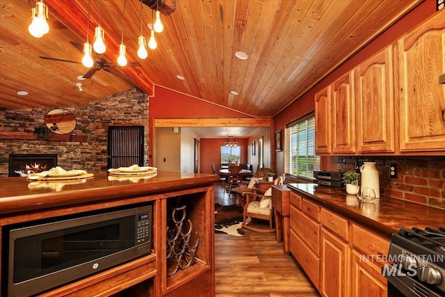 kitchen featuring light wood-style flooring, a ceiling fan, dark countertops, lofted ceiling, and built in microwave