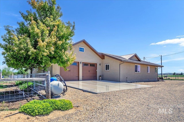 view of home's exterior with an attached garage, driveway, stucco siding, and fence