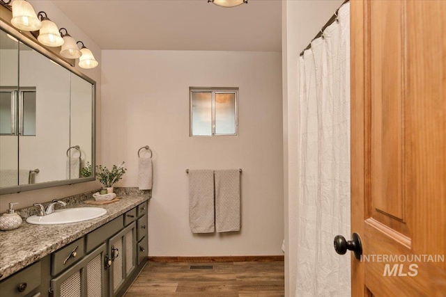 bathroom featuring wood finished floors, vanity, baseboards, and visible vents