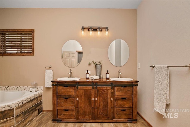 full bath featuring wood finished floors, double vanity, and a sink
