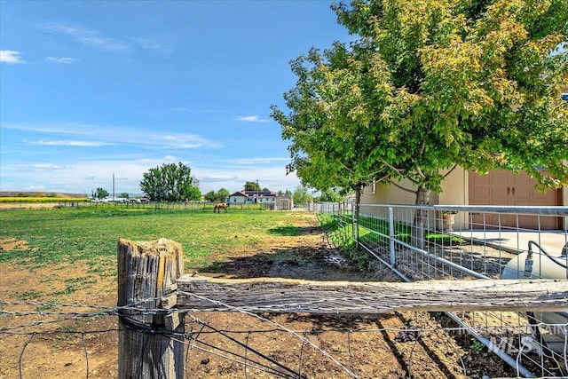 view of yard featuring a rural view, fence, and a garage