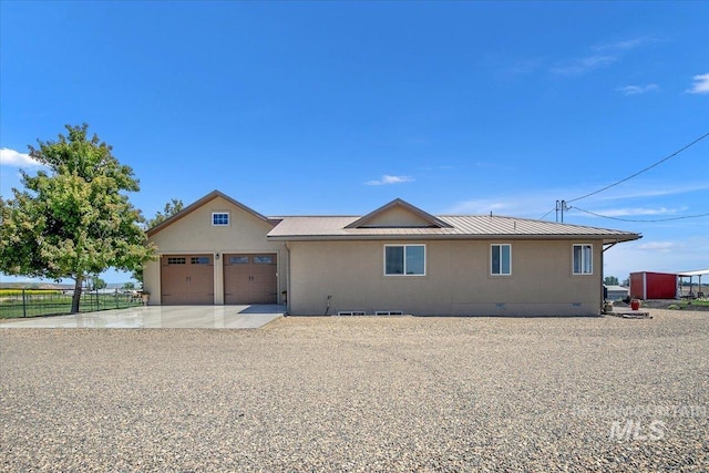 rear view of house featuring crawl space, metal roof, fence, an attached garage, and driveway