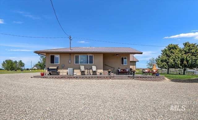 view of front of house with a patio, stucco siding, ceiling fan, metal roof, and fence