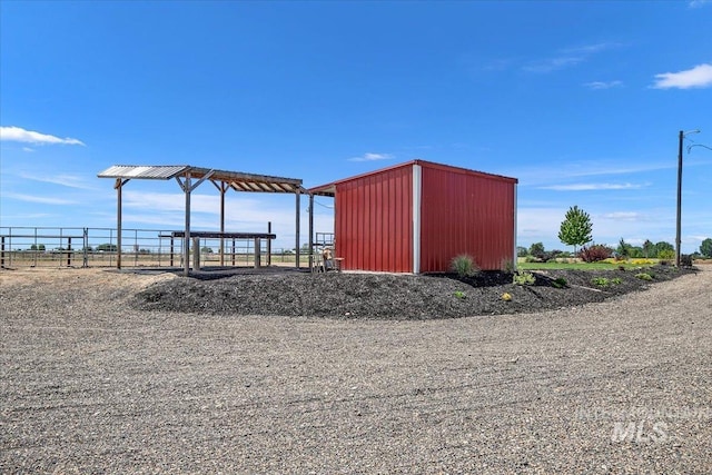 view of outdoor structure featuring a carport, fence, and an outbuilding
