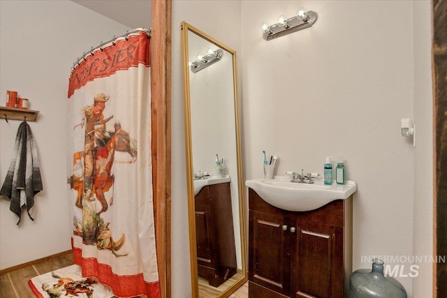 full bathroom with a shower with shower curtain, vanity, and wood finished floors