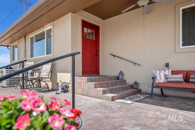 view of exterior entry featuring a patio area, stucco siding, and a ceiling fan