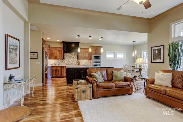 living room featuring baseboards, ceiling fan, recessed lighting, and light wood-style floors