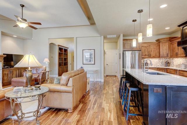 kitchen featuring a breakfast bar, open floor plan, freestanding refrigerator, light wood-type flooring, and a sink