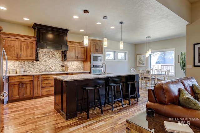 kitchen with appliances with stainless steel finishes, a breakfast bar area, a sink, and light wood-style floors