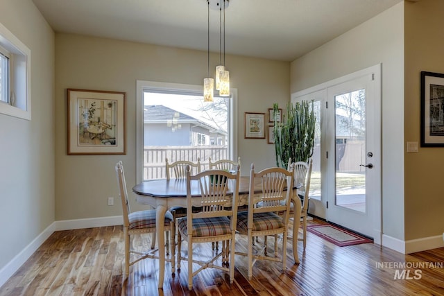 dining area with a notable chandelier, baseboards, and wood finished floors