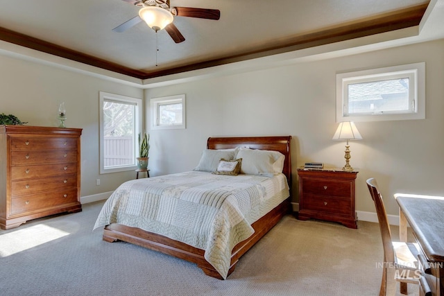 bedroom featuring a raised ceiling, light colored carpet, and baseboards