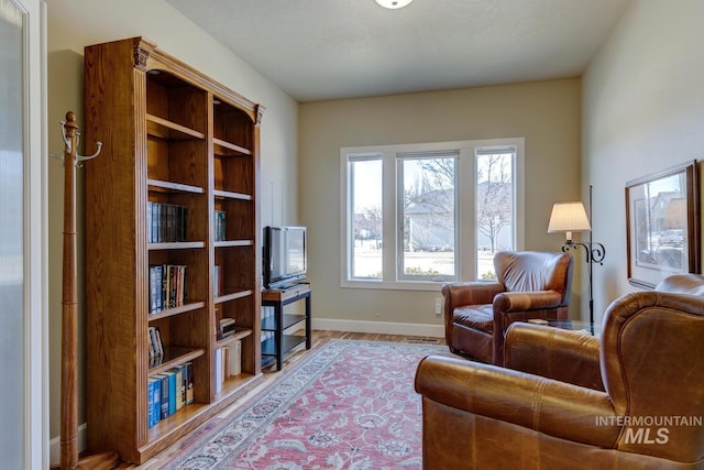 living area with baseboards and wood finished floors