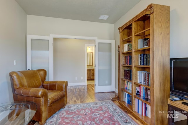 living area with french doors, baseboards, and wood finished floors