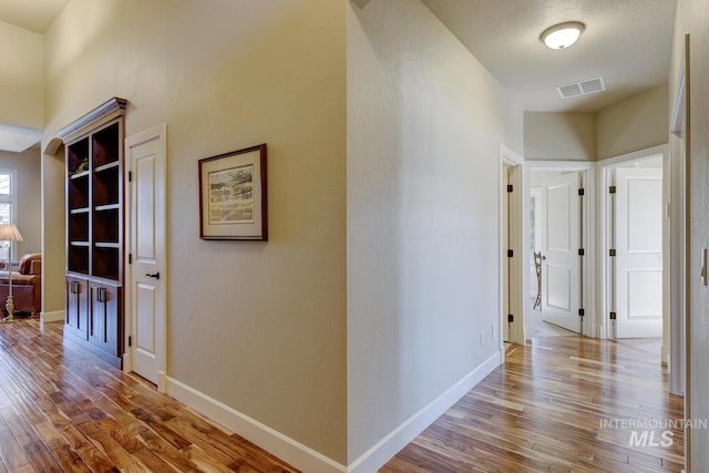 corridor with visible vents, baseboards, and wood finished floors