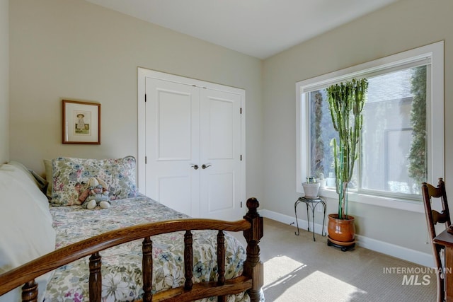 bedroom with a closet, light carpet, and baseboards