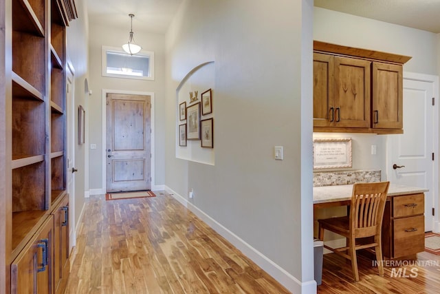 entryway with built in study area, light wood-style flooring, and baseboards