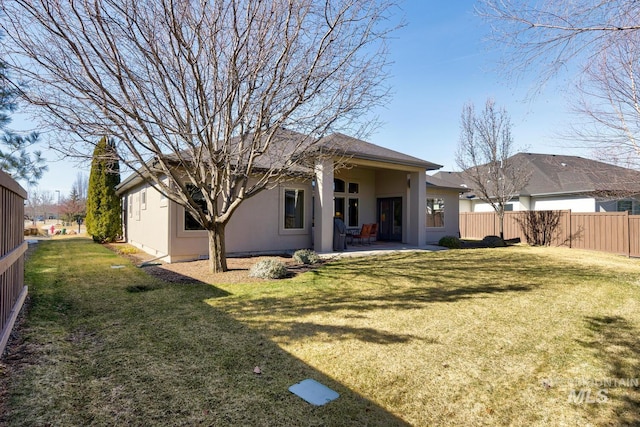 back of house with a patio area, fence, a lawn, and stucco siding