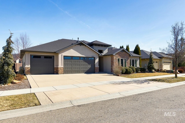 view of front of home featuring a garage, driveway, stone siding, and stucco siding