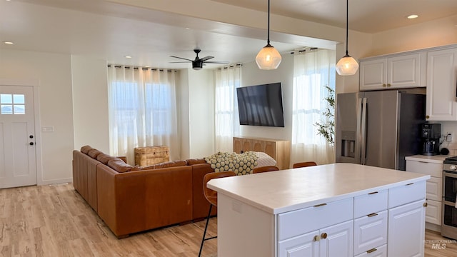 kitchen featuring white cabinetry, decorative light fixtures, appliances with stainless steel finishes, a kitchen island, and light hardwood / wood-style floors