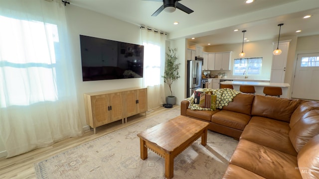 living room featuring ceiling fan, sink, and light hardwood / wood-style floors